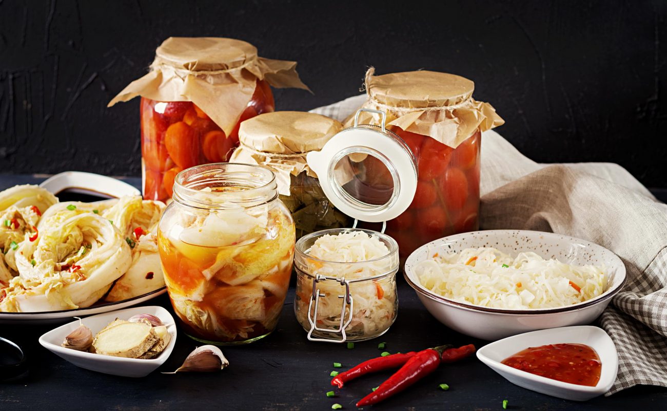 cabbage kimchi tomatoes marinated sauerkraut sour glass jars rustic kitchen table