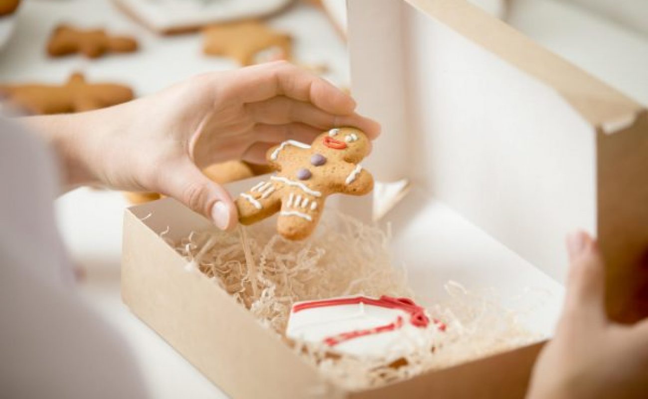 close up confectioner hand packing gingerman into box